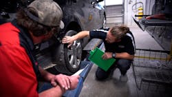 Two bodyshop technicians reviewing car repair. Two bodyshop technicians reviewing car repair.