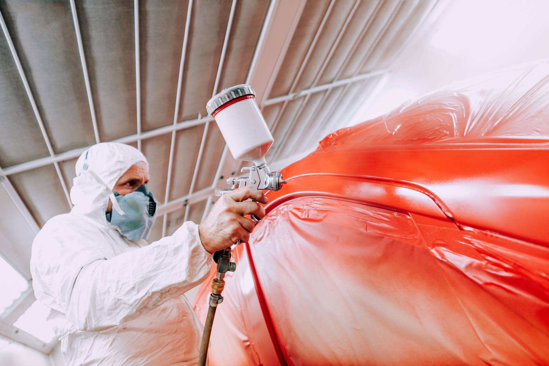 Painter with red car in booth