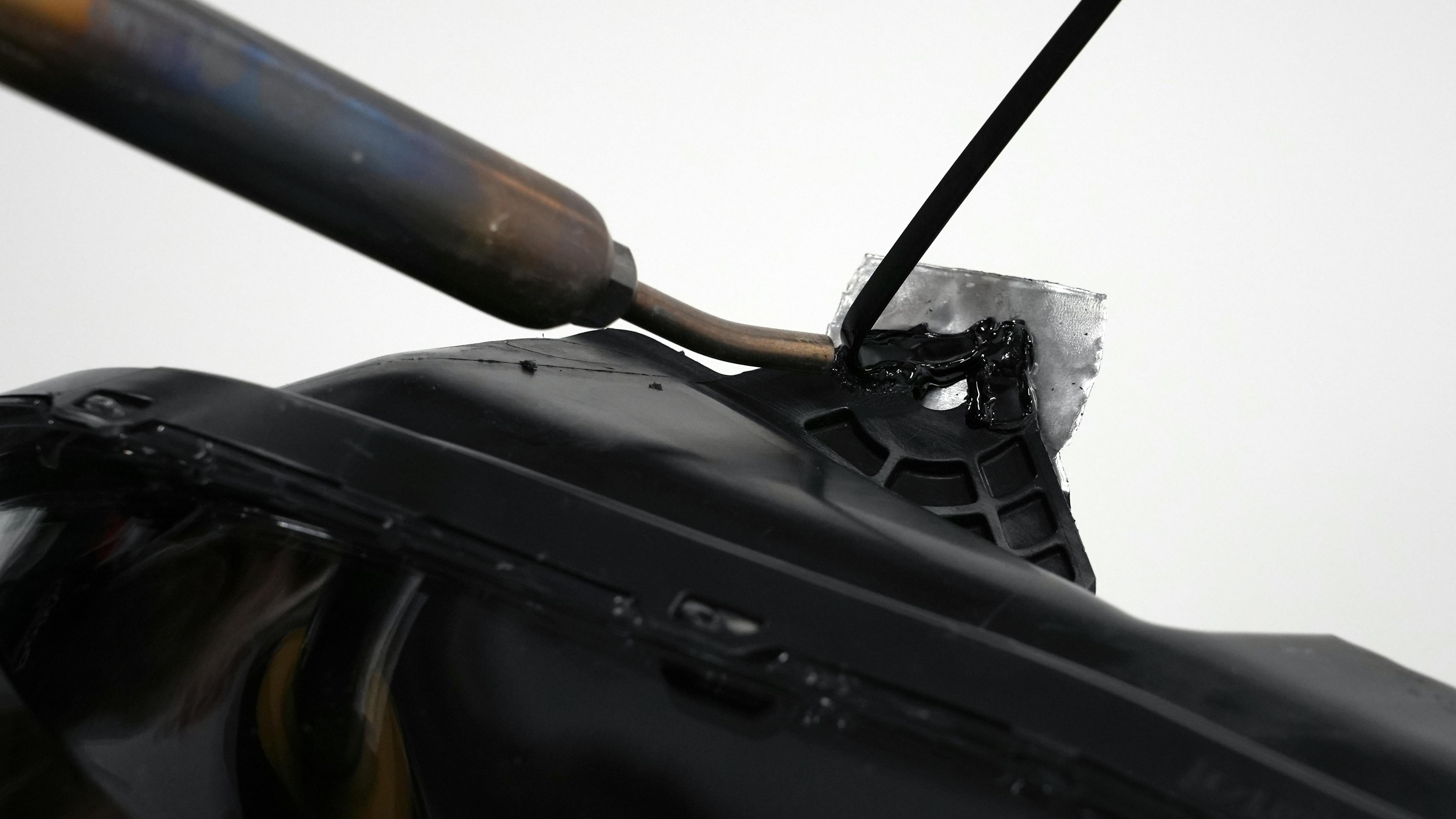 A closeup of the nitrogen welder being used to repair a headlight-mounting tab.