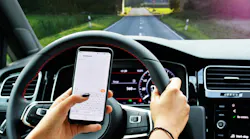 Woman texting on smartphone while driving a car on the beautiful road