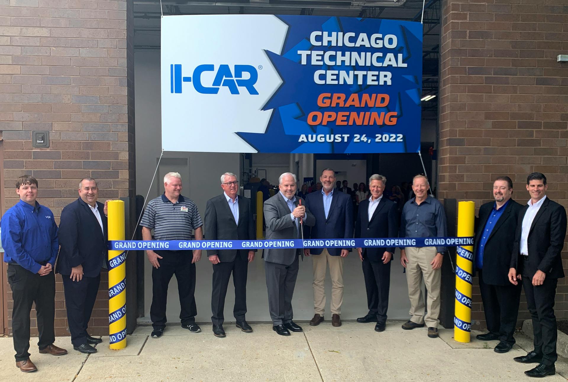I-CAR&rsquo;s Board of Directors Chair Kyle Thompson (center) is shown ready to cut the ribbon at the main entrance to the 48,000-square-foot facility. He is flanked by members of I-CAR&rsquo;s leadership, including CEO & President John Van Alstyne (fourth from right). From l. are Mike Mertes, Tom Marek, James Busam, Jeff Peevy, Thompson, Tim O&rsquo;Day, Van Alstyne, Jon Petrillo, Bud Center, and Dirk Fuchs.