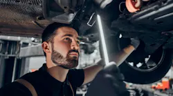 Technician inspecting under car
