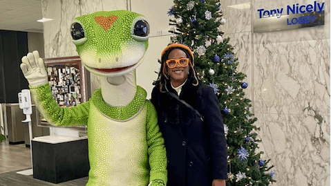 Mary Dixon stands next to GEICO mascot.