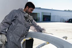 paint_tech_with_bumper_in_warehouse paint_tech_with_bumper_in_warehouse