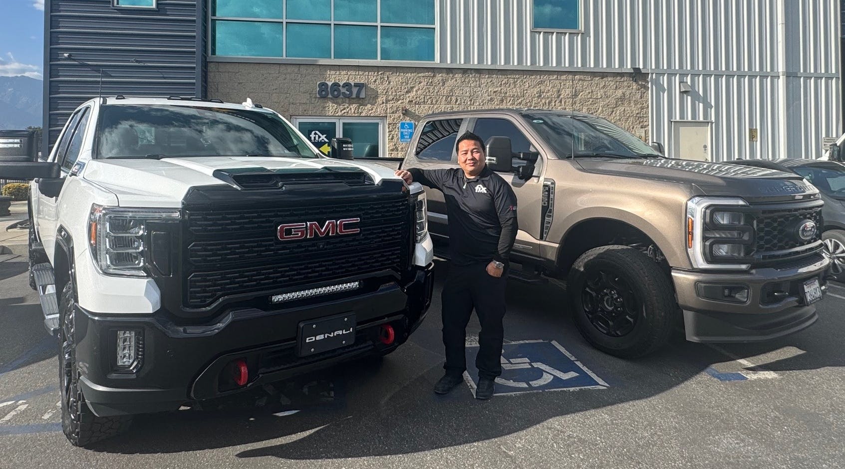 Fix Auto Fontana Owner Joe Banh poses with GM and Ford trucks.