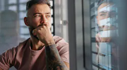 Man with tattooed arm reflecting