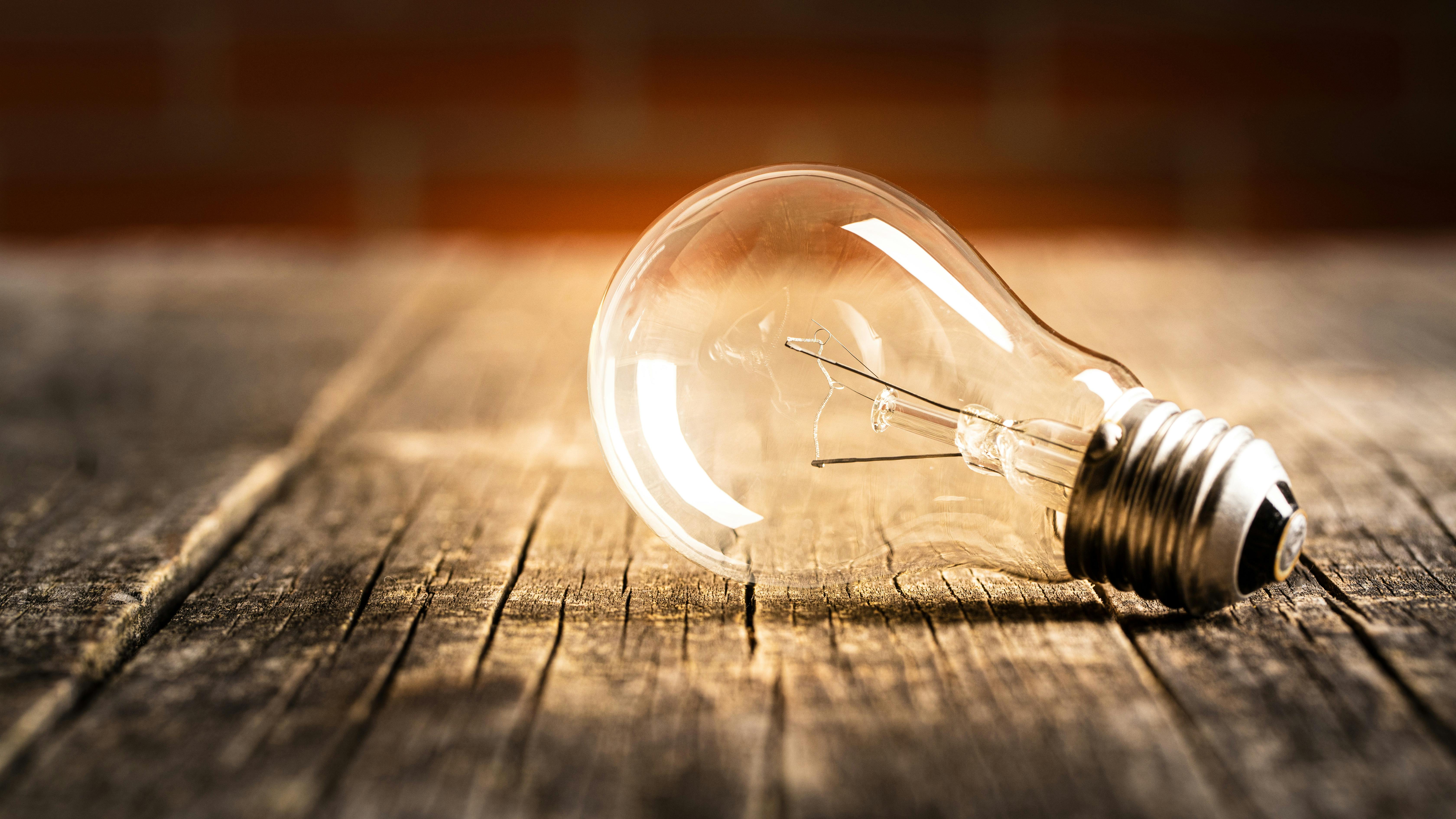 Incandescent lightbulb on old wooden planks
