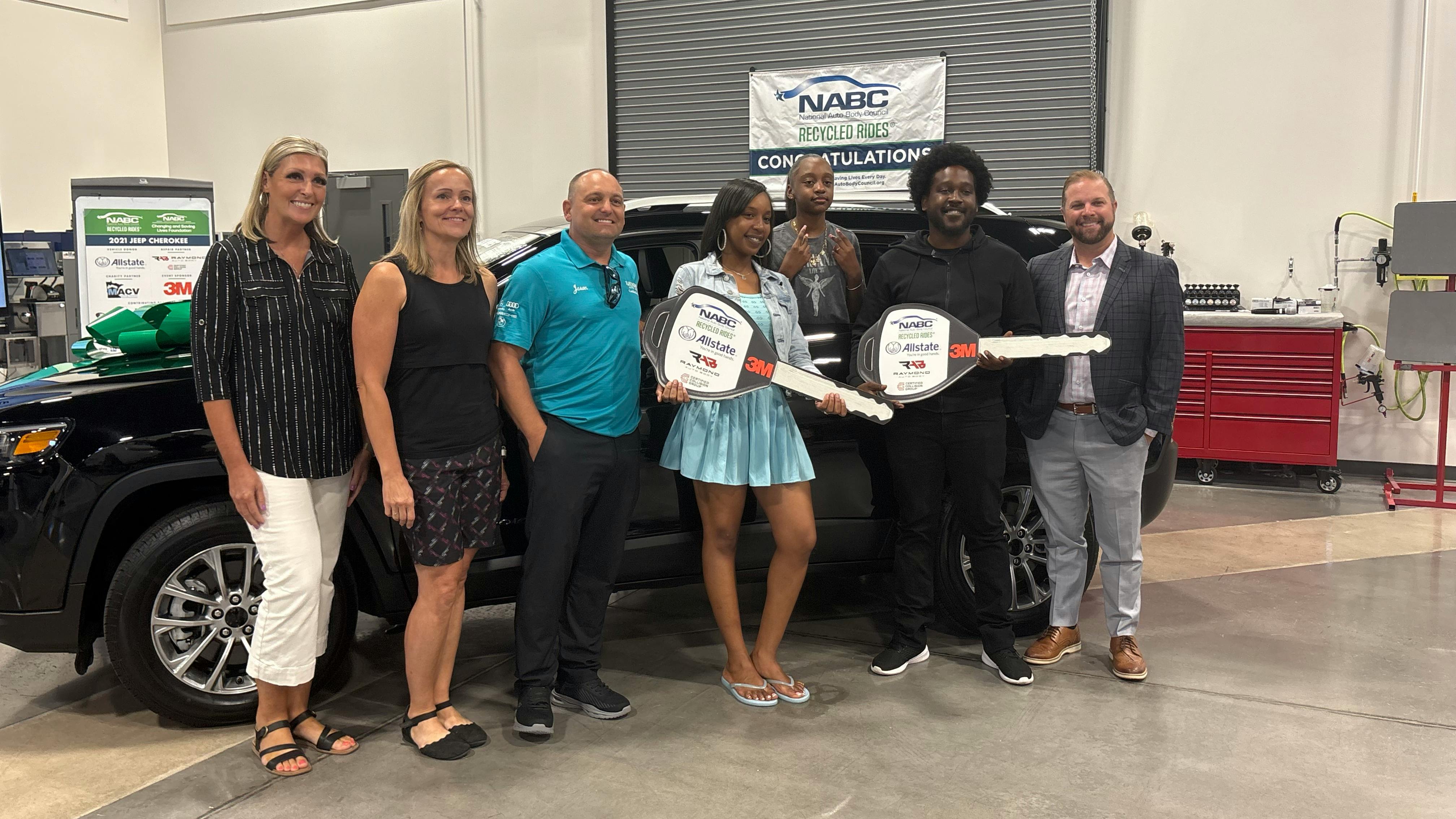 Raymond Auto Body Owner Jason Slomkowski (third from left) helps present a refurbished vehicle to U.S. Army veteran DiQuan Sanders.